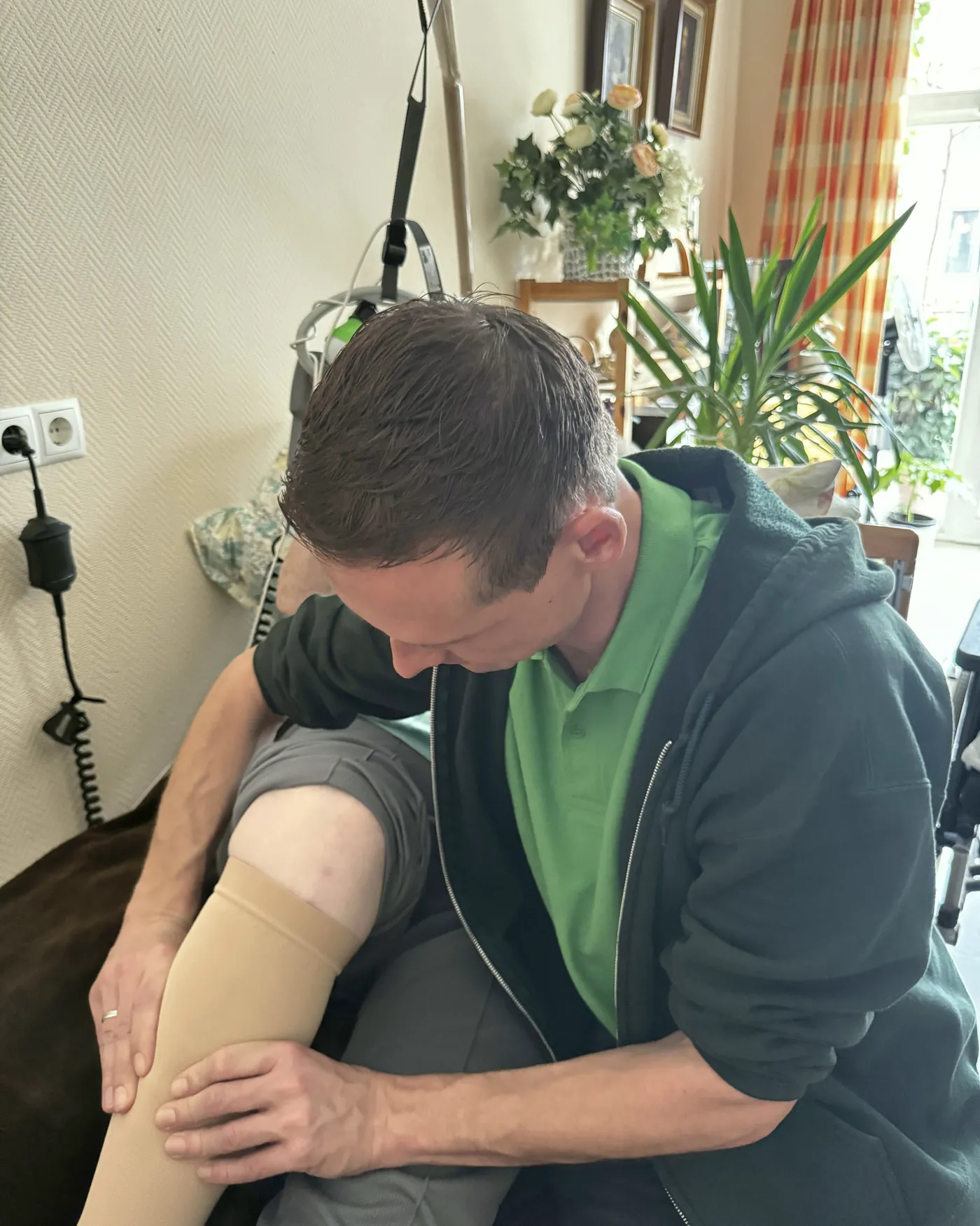 Therapeut legt beide Hände flächig an den Unterschenkel einer Patientin mit Kompressionsstrumpf