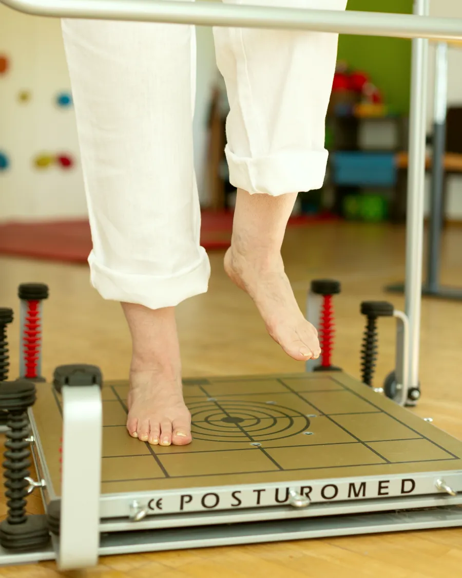 Patientin steht auf einem Bein auf dem Posturomed und übt das Gleichgewicht