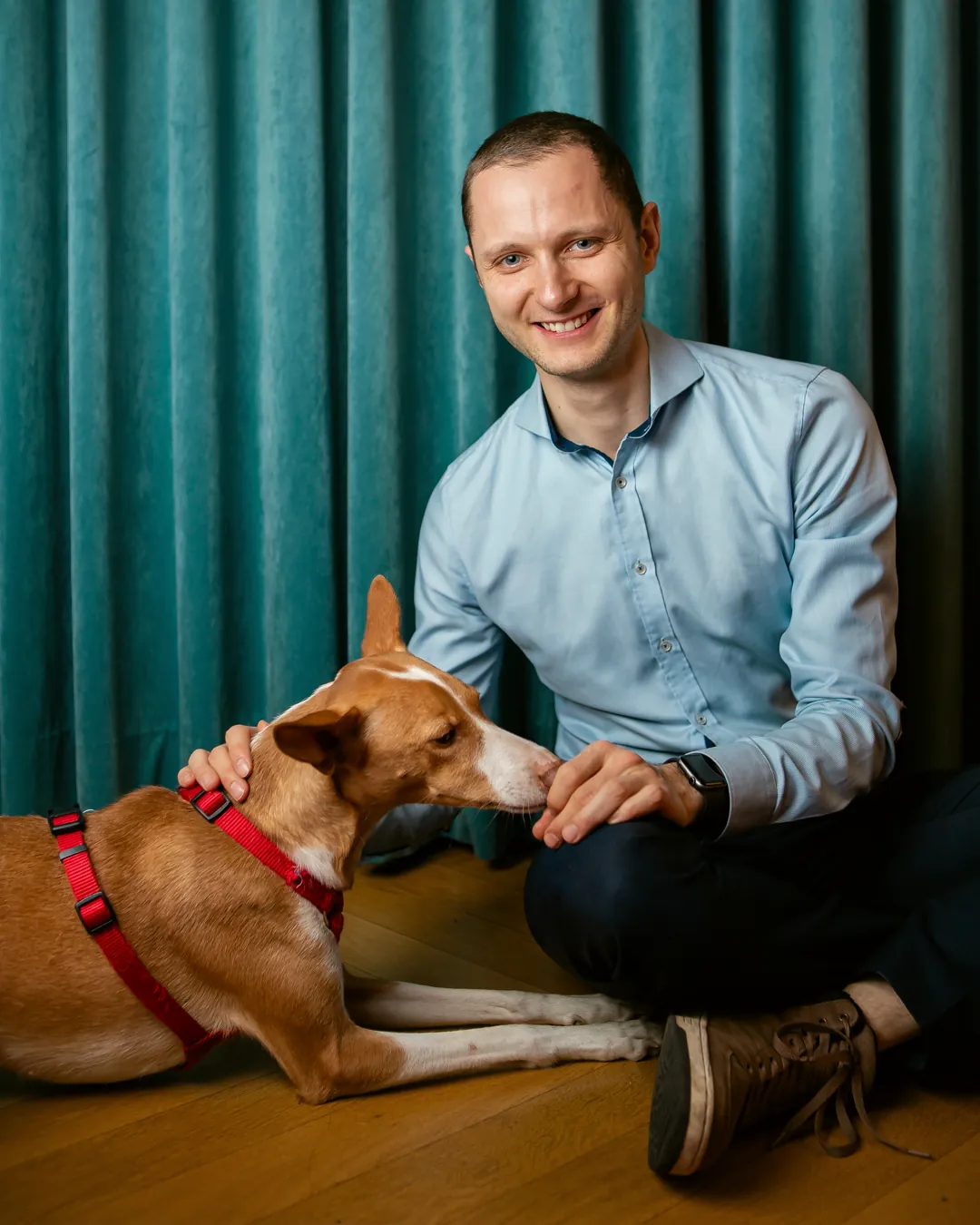 Dr. Lucas Fichter sitzt mit dem Bürohund auf dem Boden